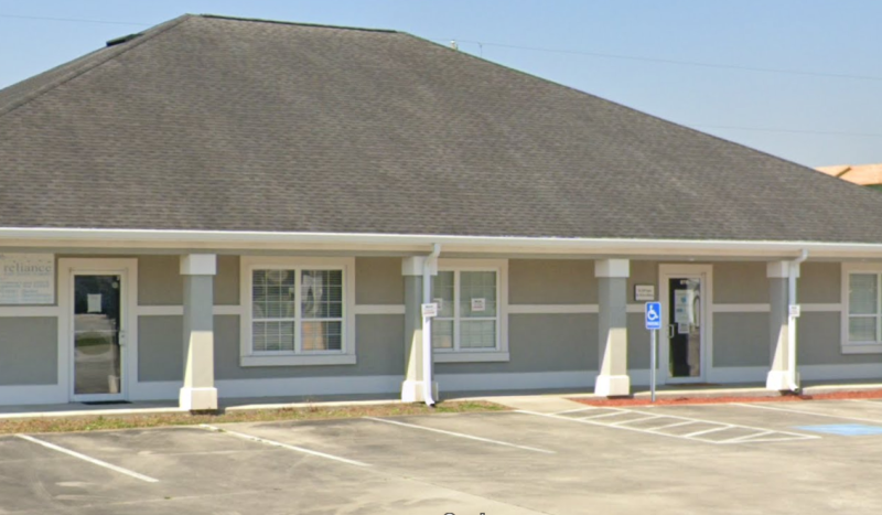 Wide exterior view of a single-story professional office building with gray siding, white trim, and a shingled roof